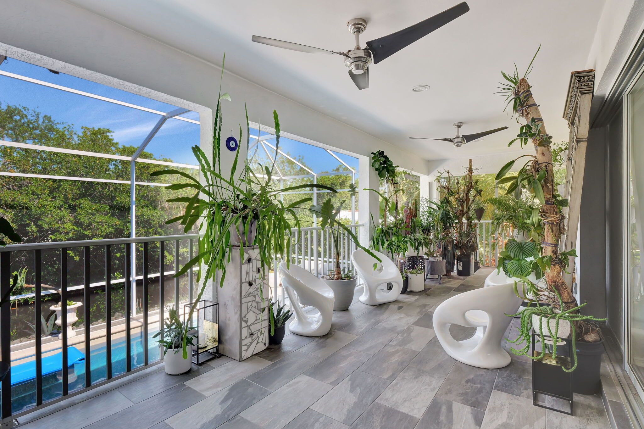 A balcony with a pool, ceiling fans, and various potted plants.