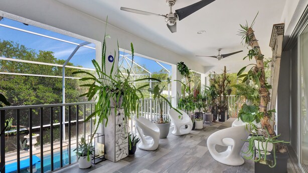 A balcony with a pool, ceiling fans, and various potted plants. - Privacy, Heated Pool, Gulf Access and Luxury! (Bonita Springs)