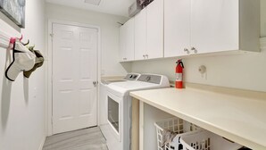 A laundry room with a washing machine, a dryer, a fire extinguisher, and a door. - Privacy, Heated Pool, Gulf Access and Luxury! (Bonita Springs)