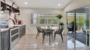 A modern kitchen with a dining area, large windows, and a view to the outside. - Privacy, Heated Pool, Gulf Access and Luxury! (Bonita Springs)