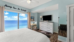 Une chambre à coucher avec un grand lit, une télévision, une commode et un bureau.