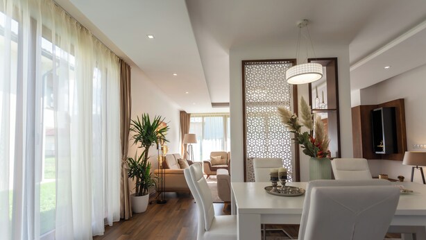 Un espace repas moderne avec une table blanche, des chaises et un vase décoratif.