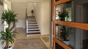Un intérieur moderne avec un escalier menant à un autre niveau, des plantes en pot et une porte en verre.