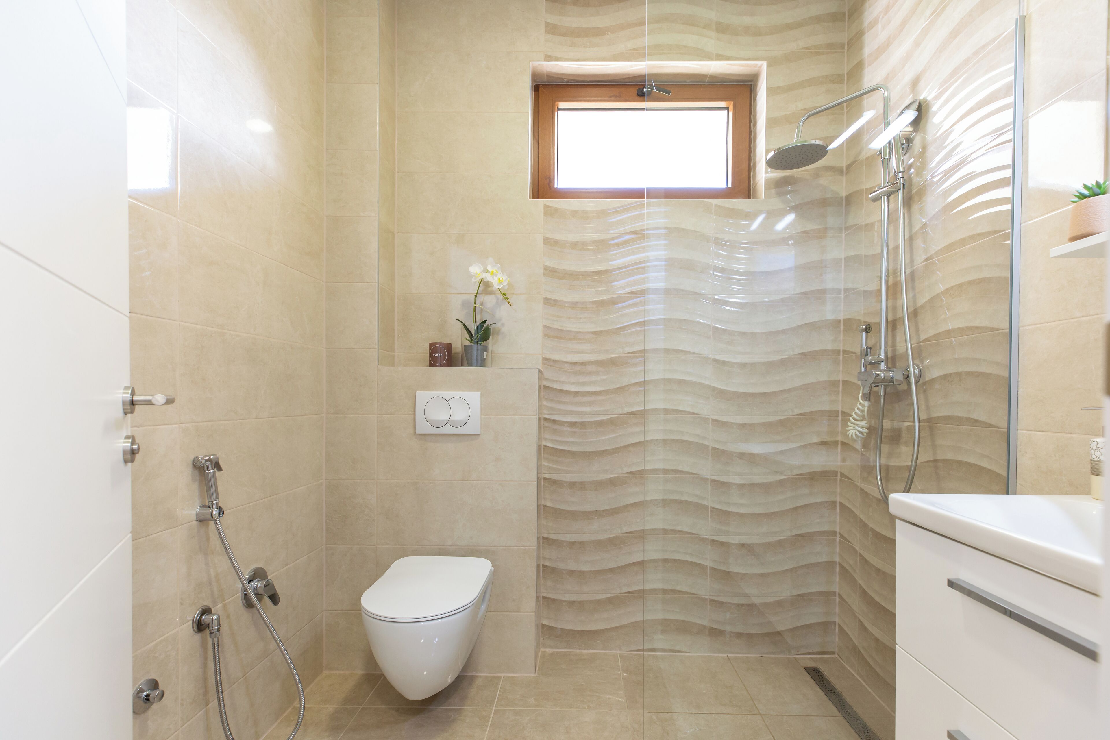 A modern bathroom with a shower, toilet, and a window.