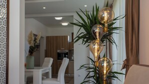 Un salon moderne avec un coin repas, agrémenté d’une plante décorée de petites lampes et d’un panneau mural décoratif.