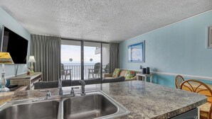 A kitchen with a granite countertop, double sink, and a view of the ocean through large windows. - Royal Garden Unit 609 -  2 Bedroom, 2 Bath Oceanfront Condo (Garden City Beach)