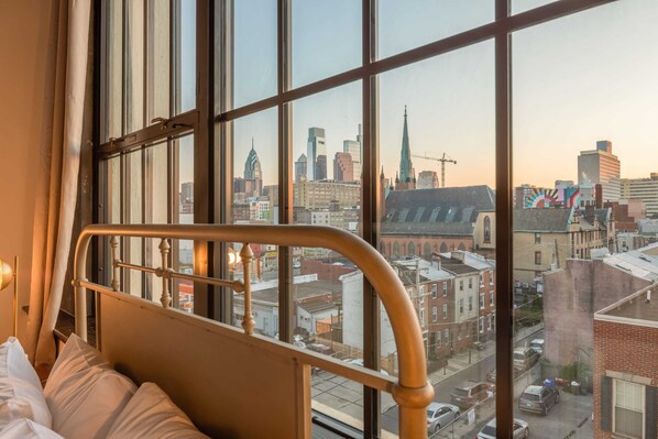 A room with a large window overlooking a cityscape, including a church spire and modern buildings.