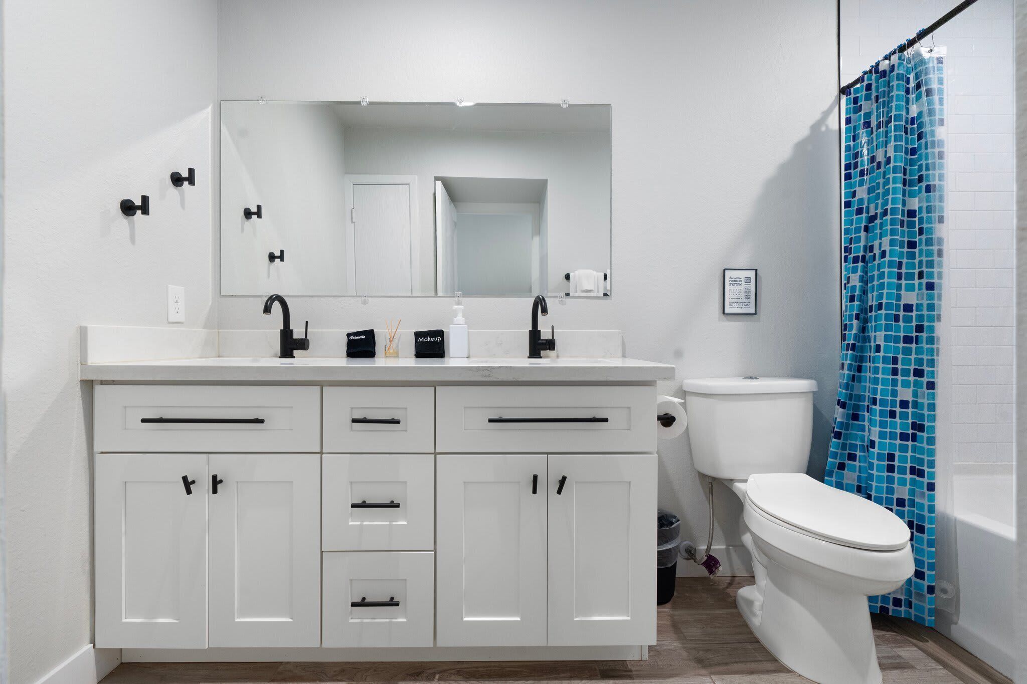 A bathroom with a white vanity, a mirror, a toilet, and a shower curtain.