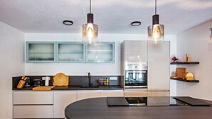 Een moderne keuken met een gebogen kookeiland, inbouwapparatuur en hanglampen.