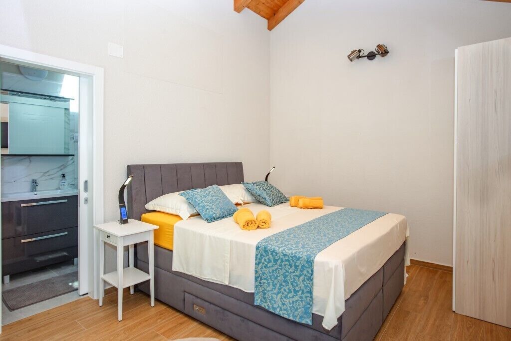 A bedroom with a bed, bedside table, and a mirror.
