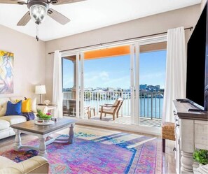 A spacious living room with a large sliding glass door leading to a balcony with a city view.