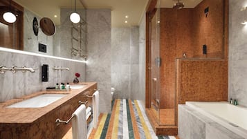 Un baño moderno con lavamanos de mármol, un espejo grande, zona de ducha y piso a rayas.