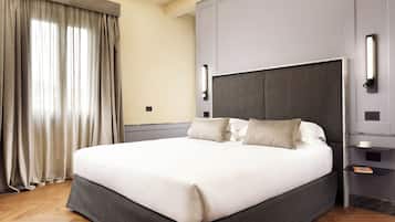 A modern hotel room with a large bed, grey headboard, and a bedside table with a lamp.