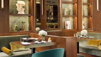 A modern interior with a seating area, a table with a meal, and decorative elements like a sculpture and a vase.