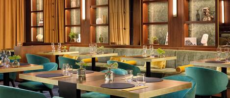 A restaurant with teal chairs and wooden tables, featuring a warm color scheme and decorative items on shelves.