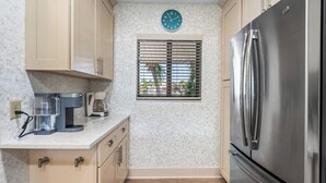 Una cocina con un refrigerador de acero inoxidable, una cafetera y un reloj en la pared.
