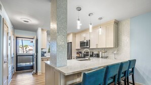 Una cocina moderna con una isla grande, electrodomésticos de acero inoxidable y taburetes de bar azules.