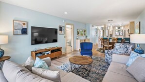 Un salón amplio con un televisor de pantalla plana grande, asientos cómodos y una zona de comedor con muebles de madera.