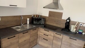 Una cocina moderna con armarios de madera, un lavamanos de acero inoxidable, un microondas, una cafetera y un tostador.