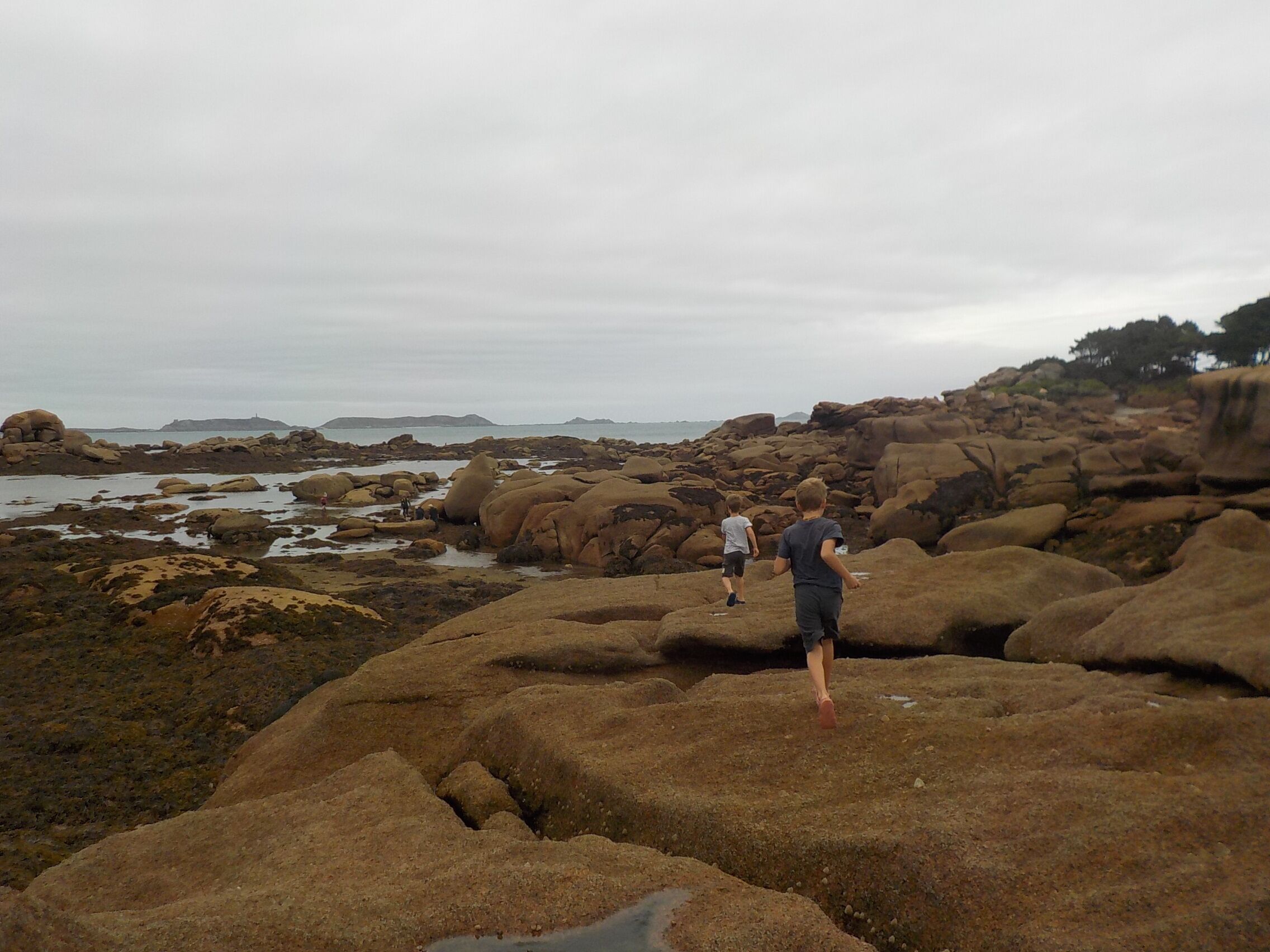 En stenstrand med stora stenblock och en avlägsen utsikt över havet.
