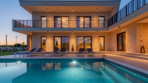 Uma casa moderna de dois andares com piscina, área de estar externa e fachada de pedra.