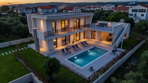 Uma casa moderna de dois andares com piscina, área de estar externa e vista para o bairro ao redor.