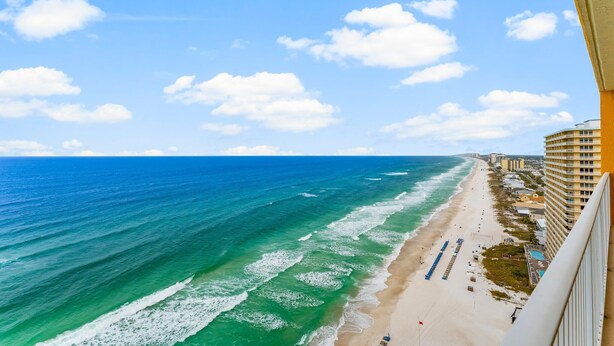 A beach with a clear view of the ocean and a row of buildings along the shore.