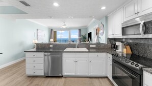 A modern kitchen with white cabinets, a stainless steel dishwasher, a black stove, and a microwave.