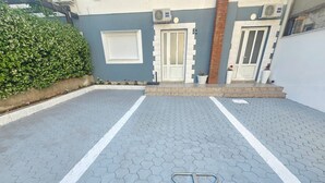 Um pátio pavimentado com um poste de metal, uma porta branca e uma pequena janela.