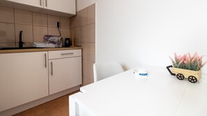 Une cuisine moderne avec des meubles de couleur beige, un plan de travail blanc et un petit chariot en bois agrémenté de plantes.