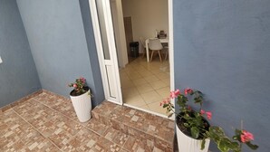 Une pièce avec un sol carrelé, une porte blanche et un bureau avec des chaises.