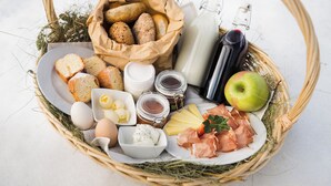 A basket containing bread, eggs, cheese, ham, and a bottle of milk. - Fantastic vacation in the Dolomites (St. Martin in Thurn)