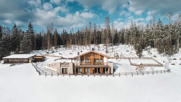 A modern log cabin with a wooden exterior, surrounded by a snow-covered landscape and a dense forest. - Fantastic vacation in the Dolomites (St. Martin in Thurn)