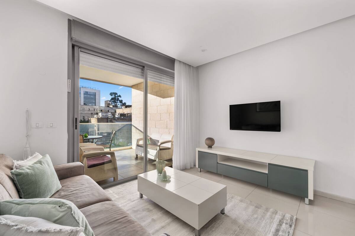 A modern living room with a sofa, coffee table, and TV stand.
