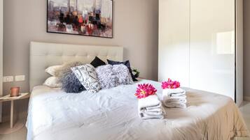 A modern hotel room with a large bed, a cityscape painting, and a wardrobe.