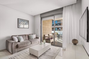 Una sala de estar moderna con un sofá, una mesa de centro y un ventanal con cortinas.