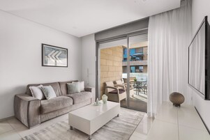 Una sala de estar moderna con un sofá, una mesa de centro y un ventanal con cortinas.