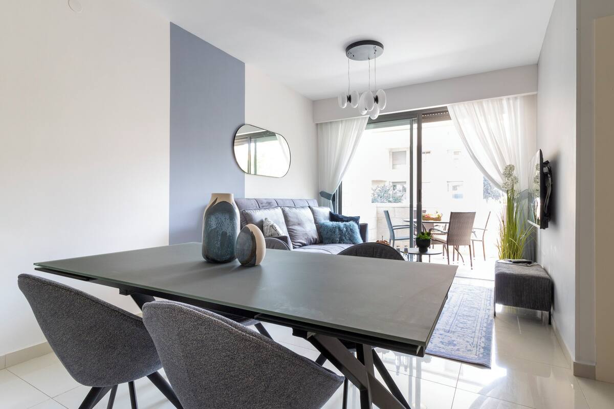 A modern dining area with a table, chairs, and a sofa.