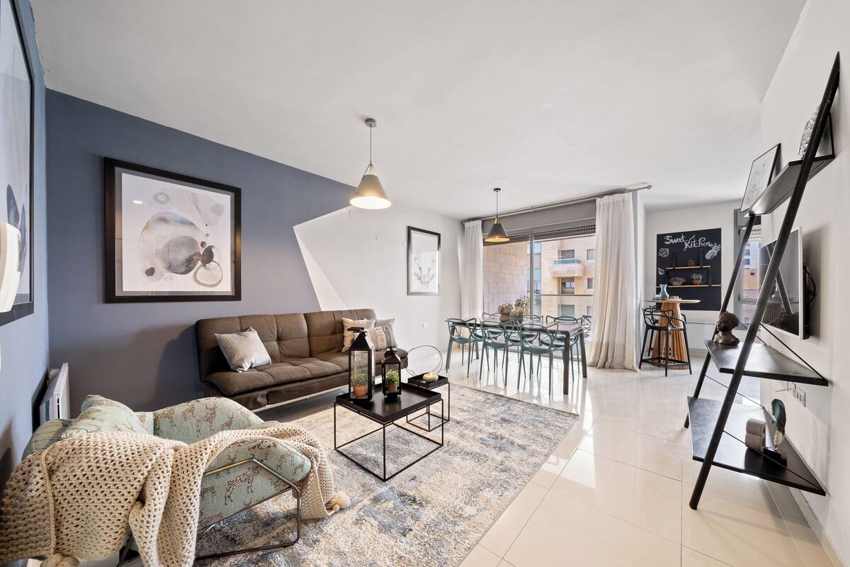 A modern living room with a sofa, coffee table, and artwork on the wall.