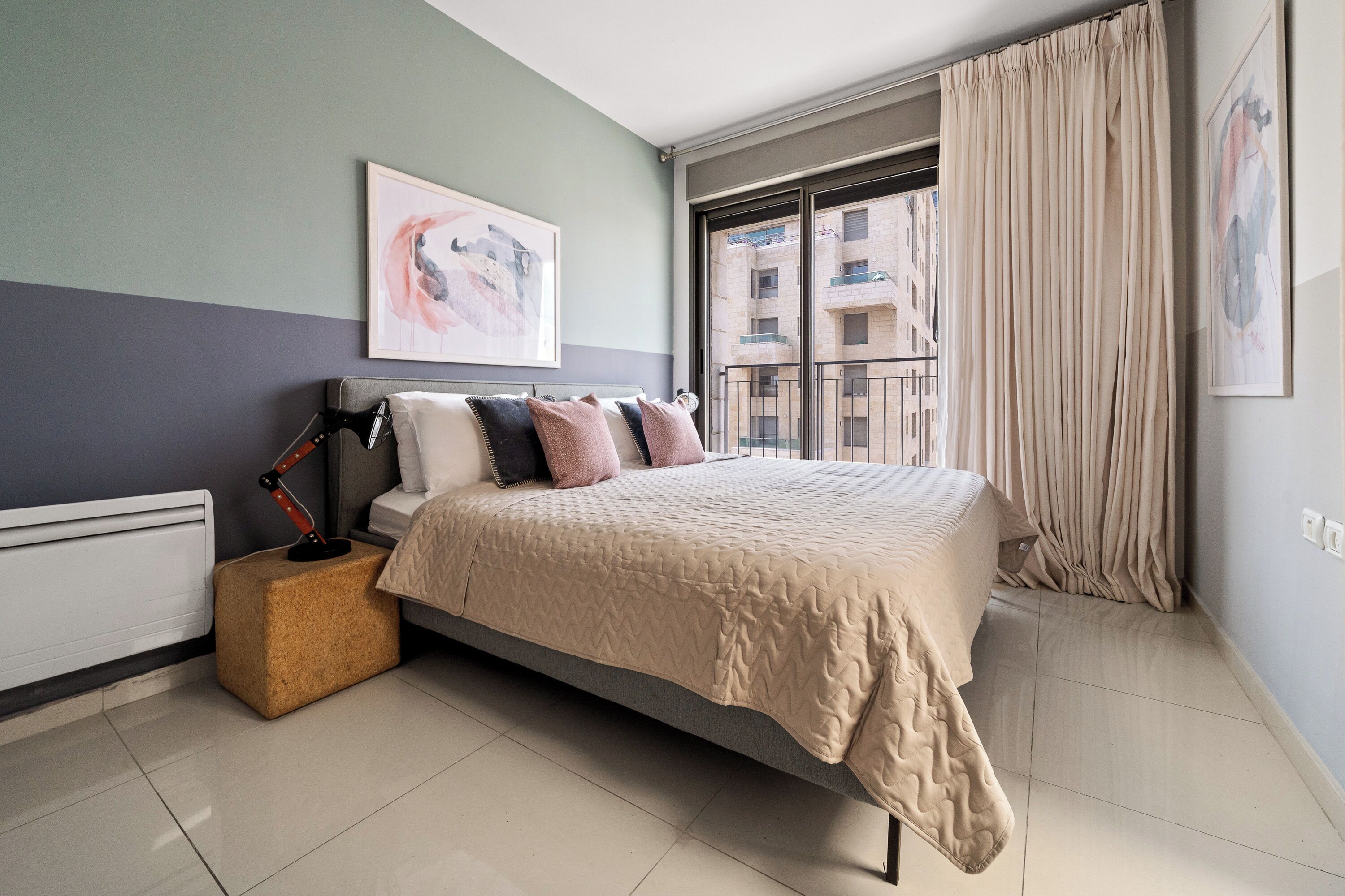 A modern bedroom with a bed, a bedside table, a lamp, and a window with curtains.