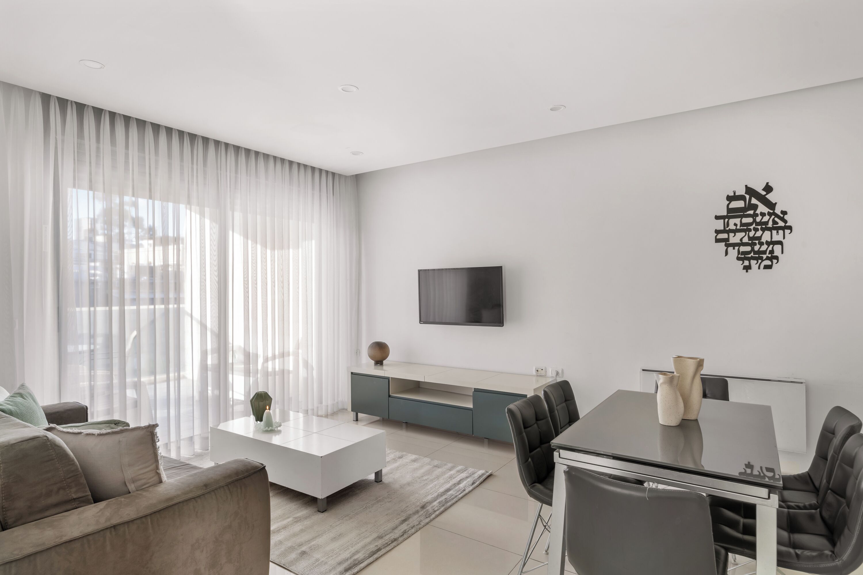 A modern living room with a sofa, coffee table, and dining table.