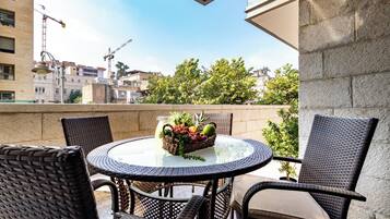A round table with wicker chairs, a fruit basket, and a clear glass top.
