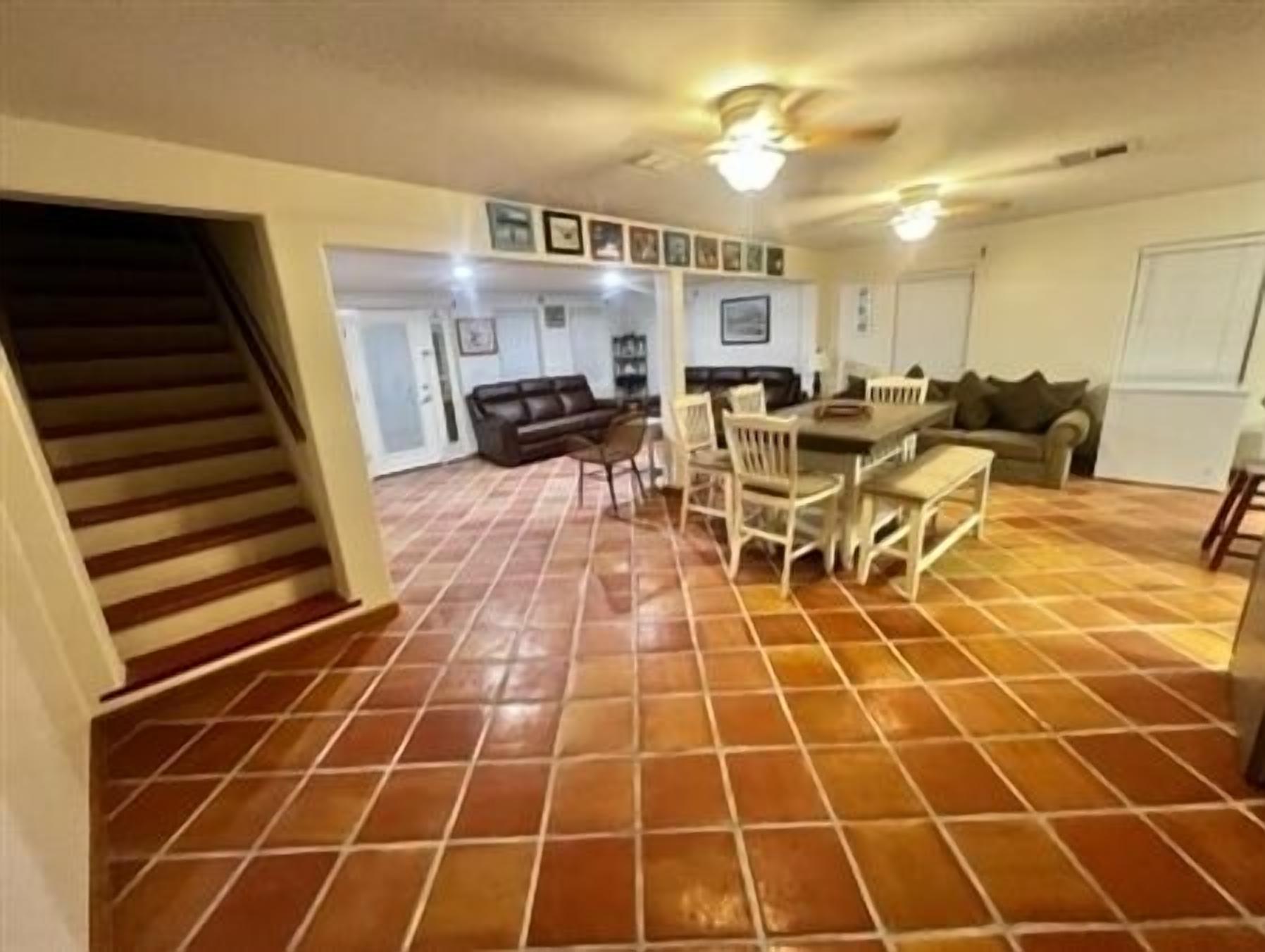 Un vaste espace de vie doté d’un sol carrelé, d’une table à manger avec des chaises, d’un canapé et d’un escalier.