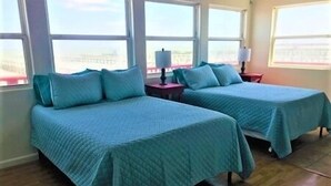 Een kamer met twee bedden, elk met een blauw bedlaken, en een nachtkastje met een lamp ertussen.