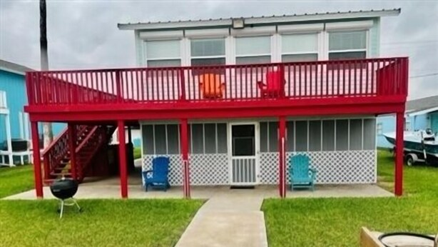 Een twee verdiepingen tellend huis met een rood balkon, een overdekte veranda en een kleine buitenbarbecue.