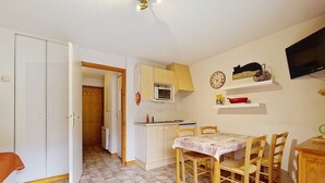 A compact kitchen with white cabinets, a microwave, and a dining area with a table and chairs.