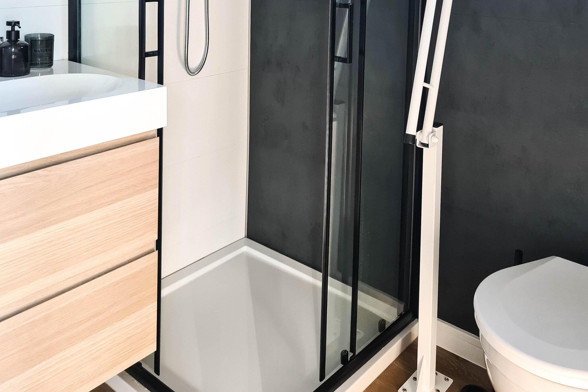 Un baño moderno con cabina de ducha, inodoro y tocador con espejo.