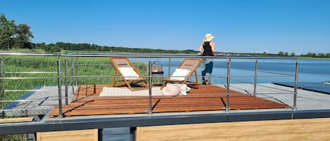 Una terraza con dos sillones, una mesa y una persona de pie.