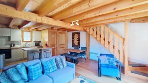 A wooden interior with a kitchen, dining area, and a staircase.