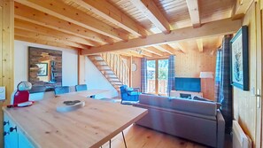 A wooden interior with a dining area, a sofa, and a television.